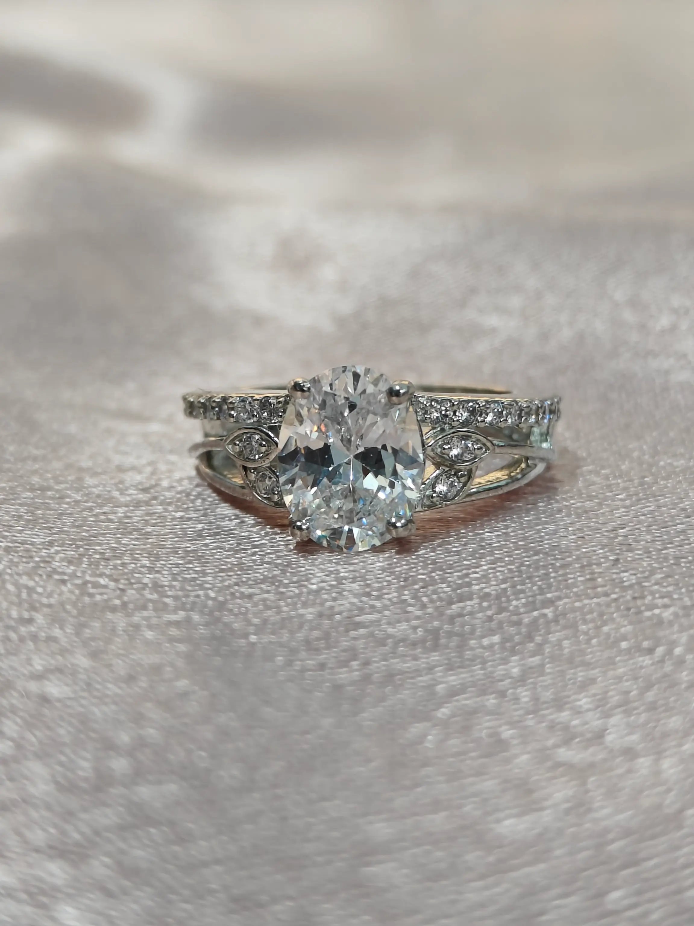 Silver ring with a large central gemstone on a textured gray surface